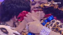 a woman in a leopard print outfit is being hugged by two other women
