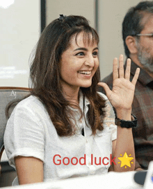 a woman is smiling and waving her hand with the words good luck above her