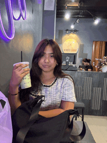 a woman holding a cup with a straw in front of a sign that says ' waste lounge ' on it