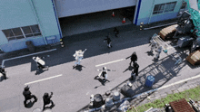 an aerial view of a group of people walking down a street in front of a building