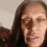 a close up of a woman 's face with her mouth open and a shadow on her face .