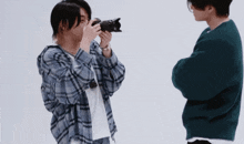 a man in a plaid shirt is taking a picture of another man with a camera