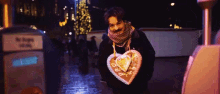 a person holding a heart shaped cookie that says ' a ' on the front
