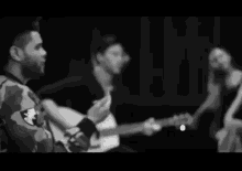 a black and white photo of a man playing a guitar next to a woman dancing .