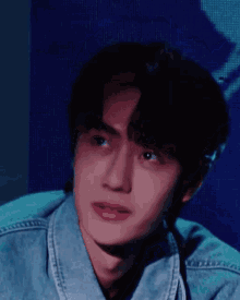a close up of a young man 's face wearing a denim jacket