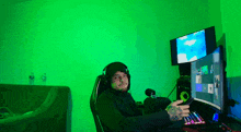 a man is sitting in front of a computer with a green background
