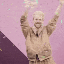 a man with a mustache and glasses is dancing with his arms in the air while confetti falls on him .