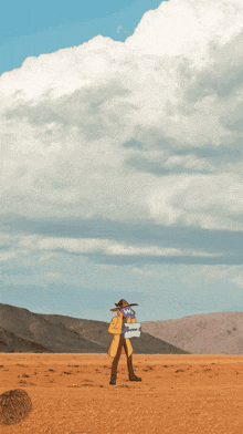a man in a cowboy hat is standing in the desert holding a sign that says ' nothing '