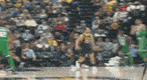 a blurred image of a basketball game with a player wearing a green jersey with the number 23