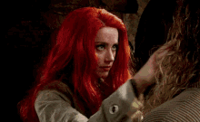 a woman with red hair is giving a high five to another person