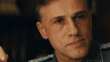 a close up of a man wearing a military uniform with the letter s on his chest