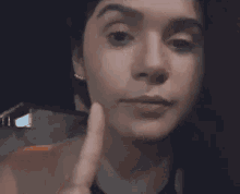a close up of a woman making a face with her hand on her chin