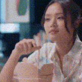 a woman in a white shirt is sitting at a table with a box of food in her hand .