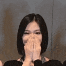a woman is covering her mouth with her hands while laughing .