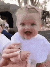 a baby with a pink bow on her head is smiling for the camera