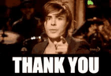 a man is pointing at the camera with the words thank you behind him .