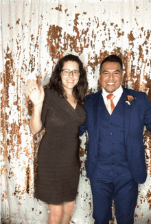 a man in a blue suit and a woman in a brown dress pose for a picture