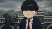 a boy in a suit and tie stands in front of a stone wall