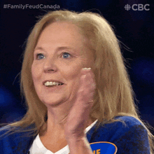 a woman wearing a blue jacket with the word family on it applauds