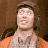 a man wearing a helmet and a scarf is making a funny face .