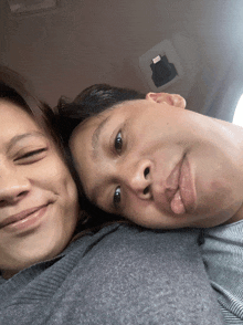 a man and a woman are posing for a picture with the man sticking out his tongue