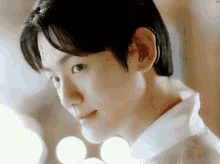 a close up of a young man 's face with a white shirt on .