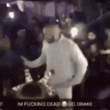 a blurry picture of a man dancing on a stage with the words `` im fucking dead go drake '' written on it .