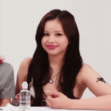 a woman sitting at a table with a bottle of water
