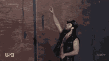 a man with a long beard is standing in front of a wall with a usa logo in the corner