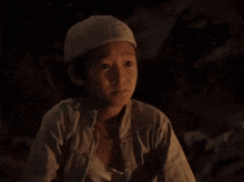 a boy wearing a white hat looks down at something