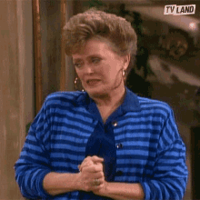 a woman wearing a blue striped sweater and a blue tie is making a funny face .