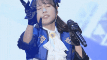 a woman in a blue jacket is singing into a microphone while making a funny face .
