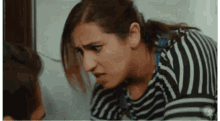 a woman in a black and white striped shirt looks at a man
