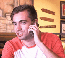 a man in a red shirt is talking on his cell phone