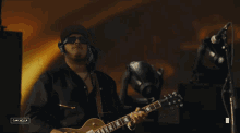 a man playing a guitar in front of a microphone with the word cancella on the bottom left