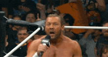 a man in a wrestling ring holds a microphone that says amw on it