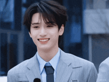 a young man wearing a suit and tie is smiling for the camera