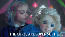 a girl holding a doll with the words " the curls are super soft "