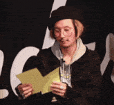 a man wearing glasses and a hat is holding a piece of paper