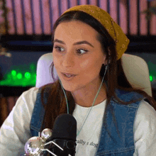 a woman wearing a bandana and a t-shirt that says locally a dog is speaking into a microphone