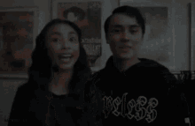 a man and a woman are posing for a picture and the man is wearing a black hoodie that says " peless "