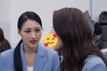 a woman kissing another woman on the cheek with a smiley face behind her