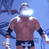 a shirtless wrestler with a cross on his trunks
