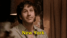 a man with curly hair is smiling and says new york in yellow letters