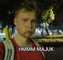 a man with a backpack making a funny face with the words hmm majuk written below him