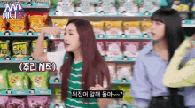 two women are standing in front of a vending machine in a store talking to each other .