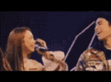 a man and a woman are standing next to each other on a stage . the woman is singing into a microphone .
