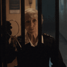 a woman in a military uniform is holding a pair of keys behind bars