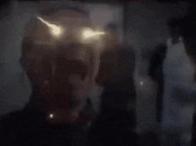 a close up of a man 's face with his mouth open and his eyes glowing in the dark .