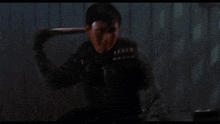 a man is holding a shotgun in front of a pink wall .